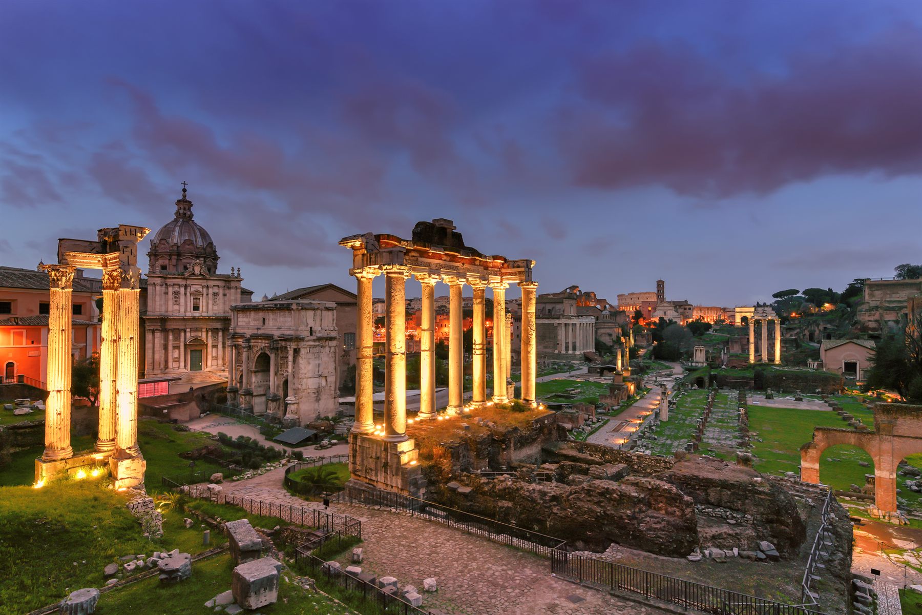 The Roman Forum’s temple columns floodlit at dusk in Rome, Italy